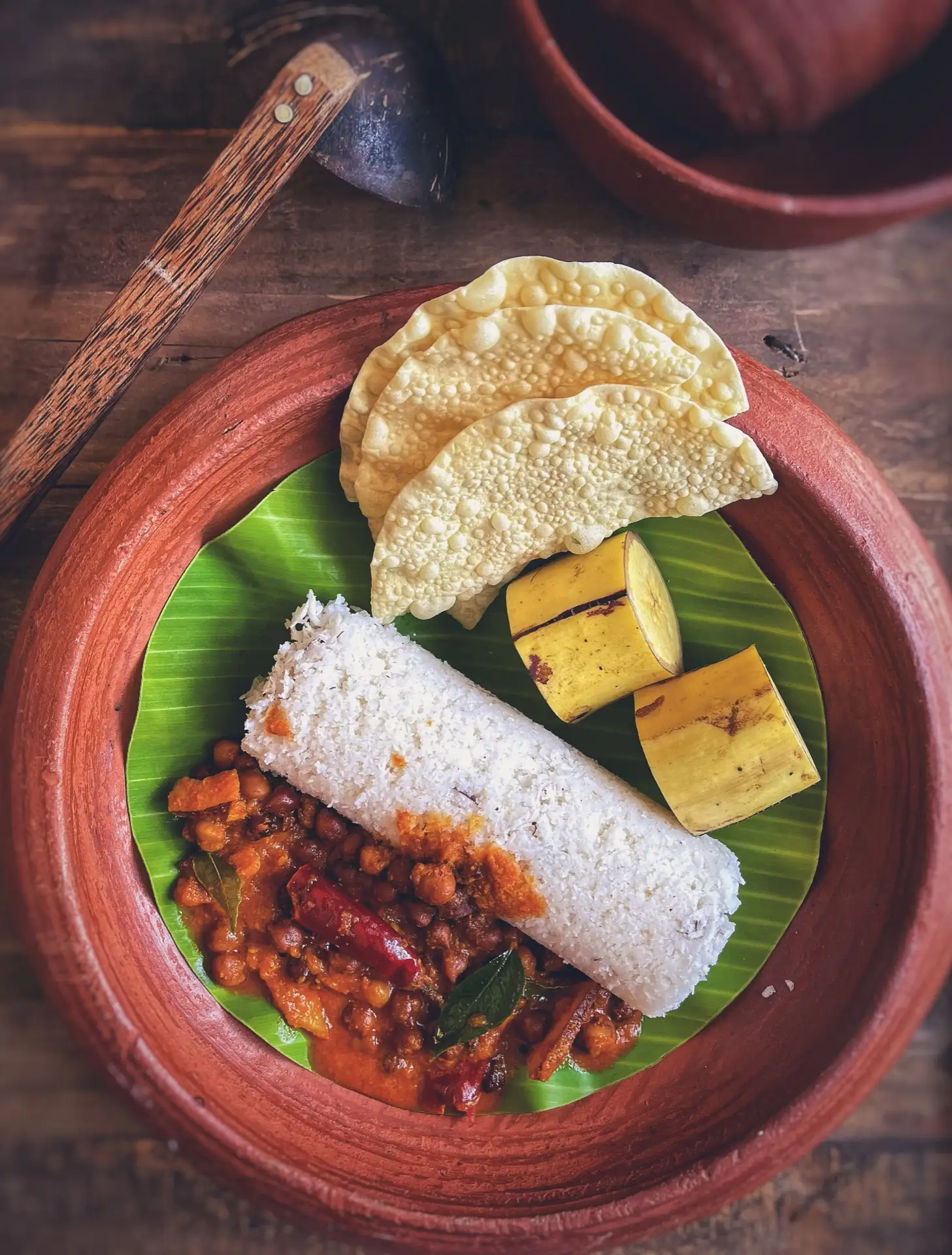 A Sri Lankan breakfast of puttu, curry, banana and poppadoms served on a banana leaf.