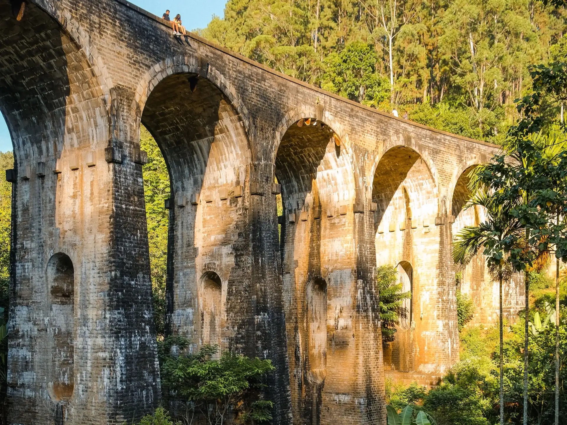 The Nine Arches Bridge curving through dense green hillside near Ella.