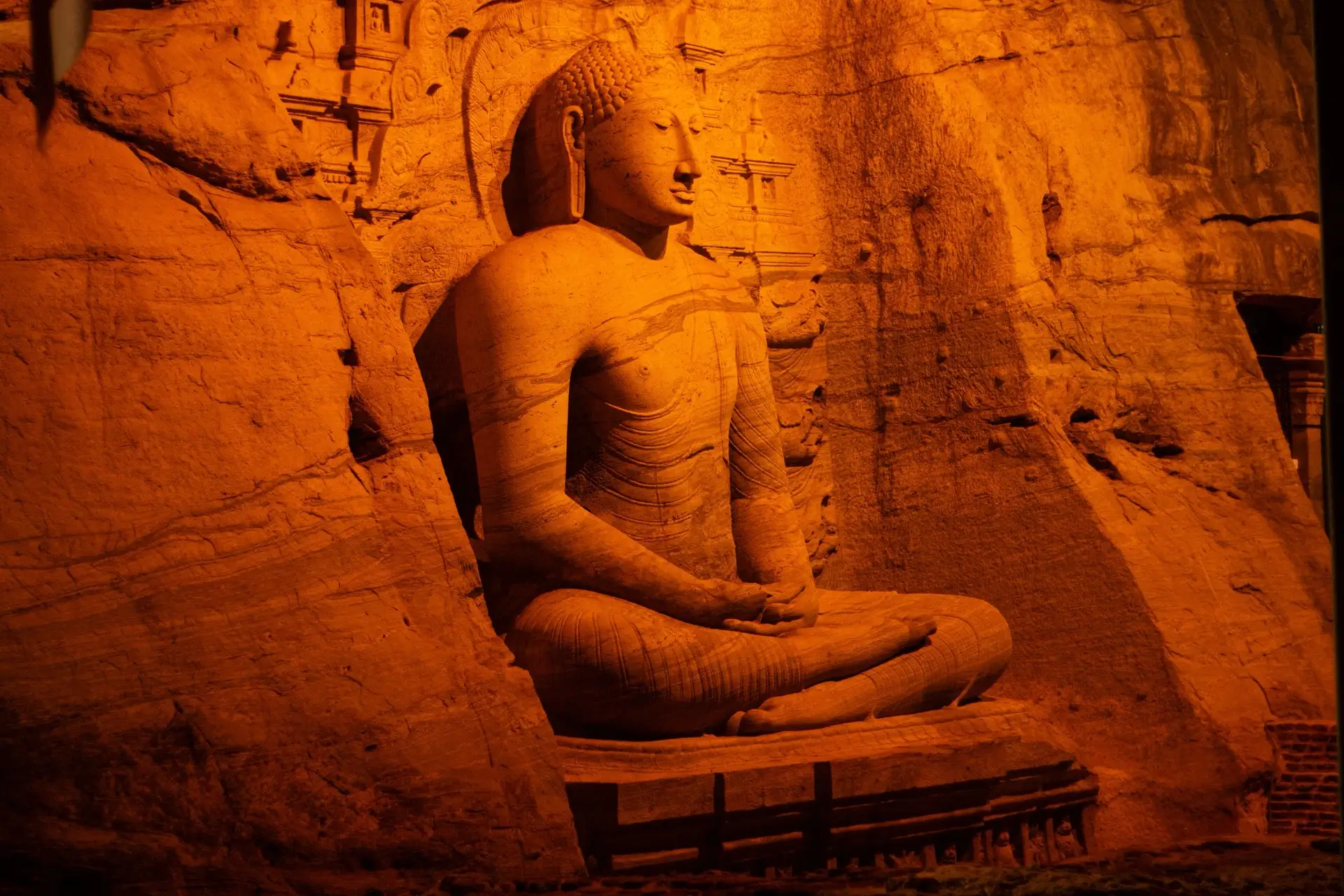 The large seated Buddha carved from the rock face at Gal Vihara, Polonnaruwa, lit warm against the granite.