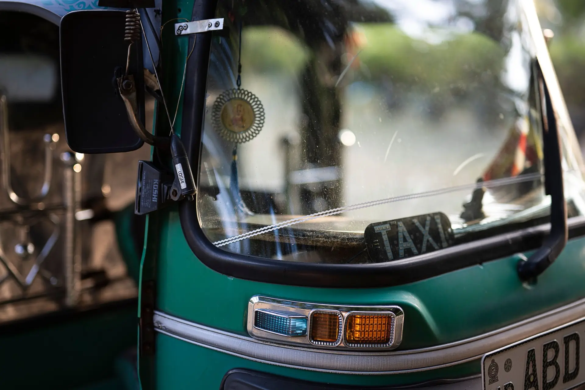 Close-up of a green tuk-tuk windscreen and handlebars in Colombo.