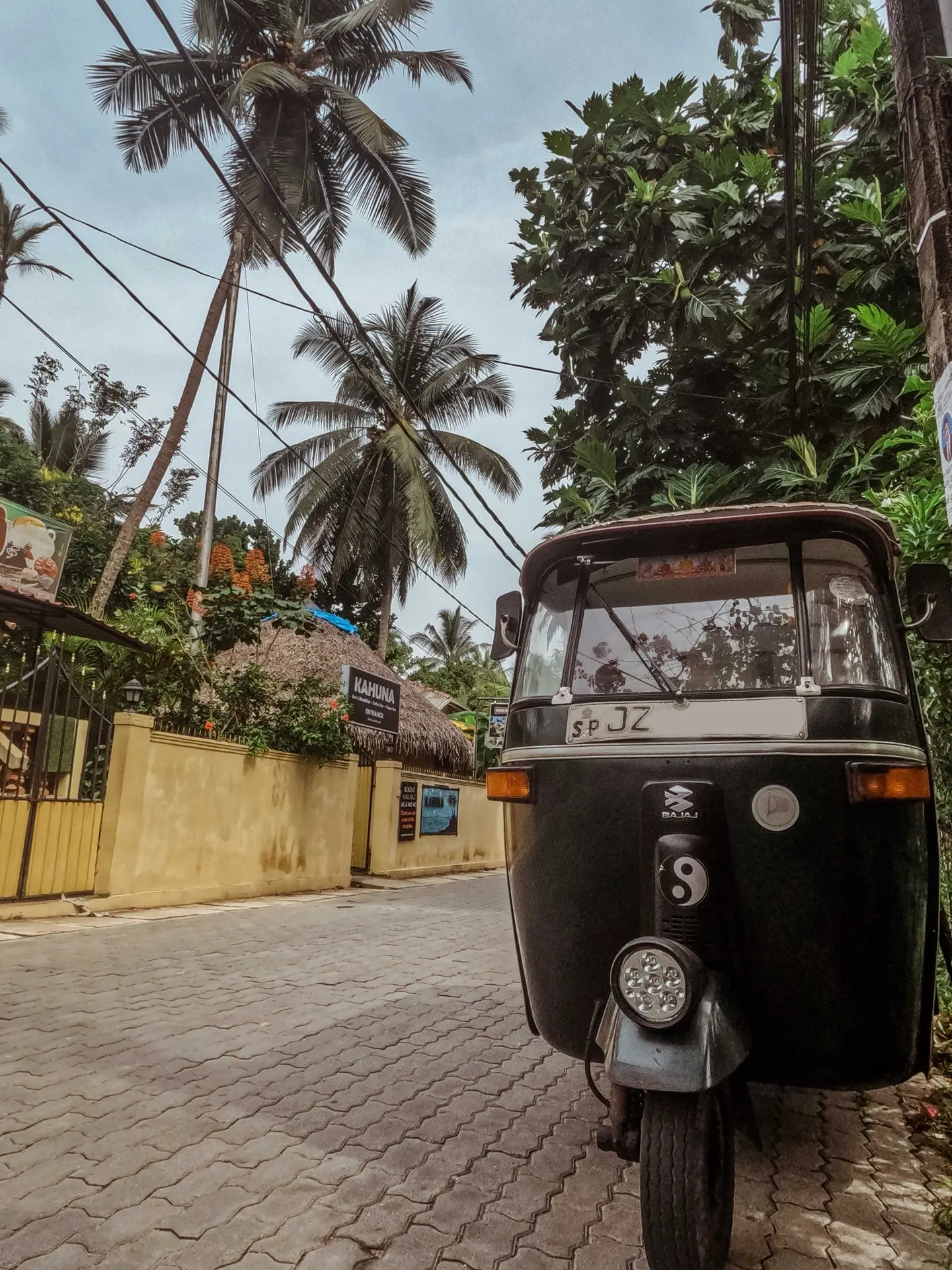 A tuk-tuk on a cobbled street lined with palm trees in Unawatuna.